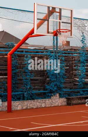 Panier de basket-ball rouge avec filet sur fond de feuilles vertes. Concept sport Banque D'Images