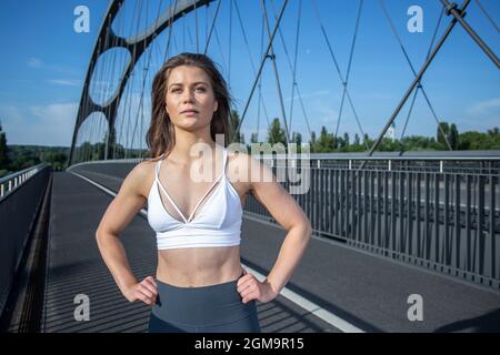 Jeune femme pratiquant le yoga dans la rue de la ville pendant la journée ensoleillée à Francfort-sur-le-main, Hesse, Allemagne. Banque D'Images