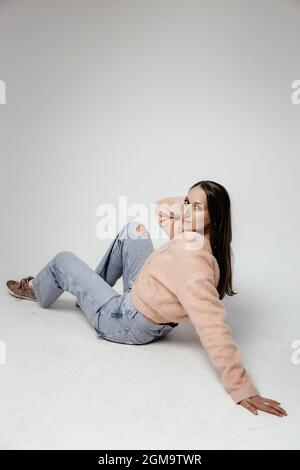 Jeune femme taille basse portant un sweat-shirt, un chapeau, un Jean et des baskets roses. Mode studio tourné. Banque D'Images
