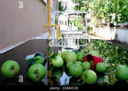 tableau des pommes vertes avec seaux colorés. seau rouge et bleu plein de pommes fraîchement récoltées. Banque D'Images