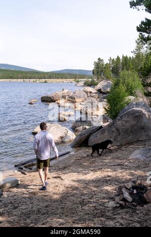 Wyoming, États-Unis - 6 août 2021 : un homme et son chien Labrador retriever noir marchent le long du rivage du réservoir de Worthen Meadow, près de Lander Banque D'Images