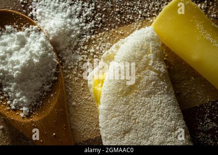 Tapioca, un plat typiquement brésilien, avec garniture de mozzarella sur la planche à découper et une cuillère en bois avec de la farine et une tranche de mozzarella roulé. Banque D'Images