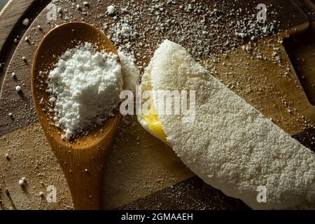 Tapioca, un plat typiquement brésilien, avec garniture de mozzarella sur une planche à découper et une cuillère en bois remplie de farine. Plat à base de farine. Banque D'Images