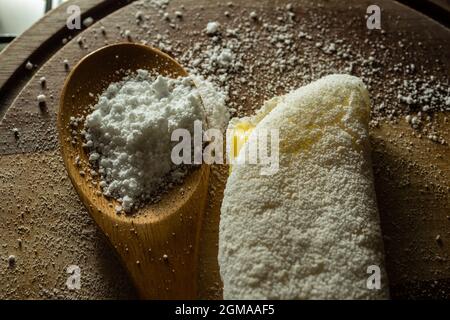 Tapioca, un plat typiquement brésilien, avec garniture de mozzarella sur une planche à découper et une cuillère en bois remplie de farine. Plat à base de farine. Banque D'Images