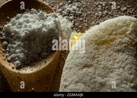 Tapioca, un plat typiquement brésilien, avec garniture de mozzarella sur une planche à découper et une cuillère en bois remplie de farine. Plat à base de farine. Banque D'Images