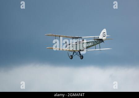 G-AAHI - a 1929 de Havilland DH-60G Gypsy Moth voler bas et lent sous ciel nuageux Banque D'Images