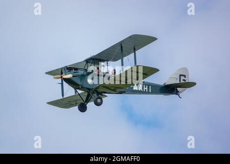 G-AAHI - a 1929 de Havilland DH-60G Gypsy Moth voler bas et lent sous ciel nuageux Banque D'Images