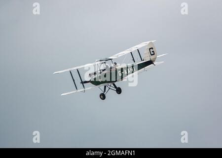 G-AAHI - a 1929 de Havilland DH-60G Gypsy Moth voler bas et lent sous ciel nuageux Banque D'Images