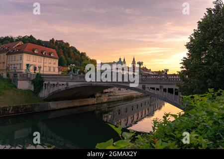 Pont Dragon à Ljubljana au coucher du soleil avec le château et la cathédrale . Banque D'Images