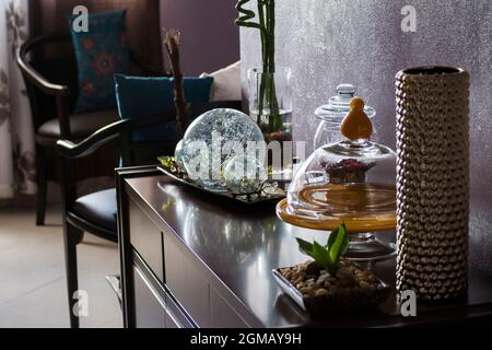 Intérieur d'un appartement décoré avec divers objets en verre, bois et plastique. Les chaises, les tables et les photos font partie de la décoration. Banque D'Images