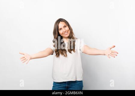 Venez ici, je vais vous donner un câlin. Portrait d'une femme avec les bras larges ouverts sur fond blanc. Banque D'Images