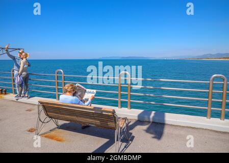 personne lisant le journal sur un banc avec vue sur la mer - un couple prend un selfie en face de la mer sur la vue incroyable de la jetée de forte dei marmi à versilia Banque D'Images