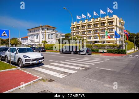 Quelques voitures de luxe passent le long de la route côtière en face des hôtels 4 et 5 étoiles et des résidences de luxe forte dei Marmi, riviera, Lucca Toscane, Italie Banque D'Images