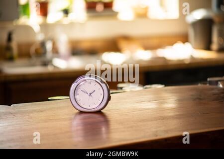 horloge sur comptoir en bois dans la cuisine avec fenêtre et herbes en arrière-plan Banque D'Images