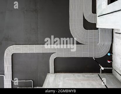 Câbles et tuyaux électriques sur fond de plafond en béton de la maison, tuyaux en plastique avec fils dans la pièce vide. Lignes de tubes de câblage en pvc après professionnel Banque D'Images