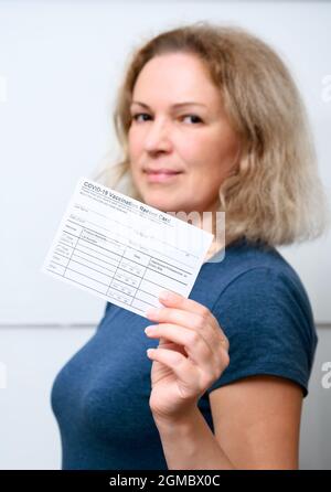 Jeune femme vaccinée présentant la carte de vaccination COVID-19, bonne personne après avoir reçu le vaccin contre le virus corona. Concept de vaccin contre le coronavirus, Banque D'Images