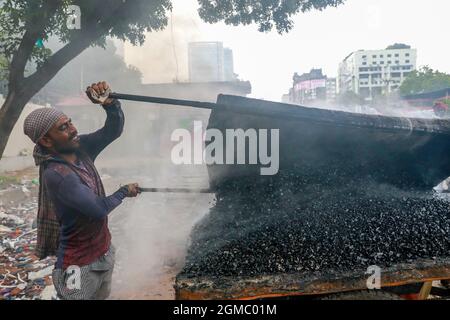 Dhaka, Bangladesh. 17 septembre 2021. DHAKA, BANGLADESH - 17 SEPTEMBRE 2021 : Un travail de route migrant fond des minéraux d'asphalte sur de petites pierres pour faire un mélange dans le cadre du resurfaçage d'une route dans l'une des banlieues de Dhaka, les employés travaillent dur plusieurs heures au soleil pour maintenir les rues et les routes de la ville en bon état. Le 17 septembre 2021 à Dhaka, au Bangladesh. (Photo de Tanvir Ahammed/ Eyepix Group) crédit: EYEPIX Group/Alamy Live News Banque D'Images