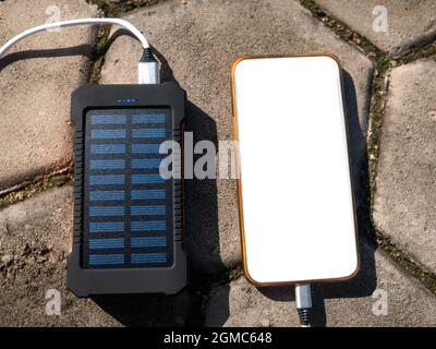 Bloc d'alimentation mobile rechargeable avec panneaux solaires, gros plan. Connecté à un téléphone portable, une tablette ou un smartphone et en charge. Banque D'Images