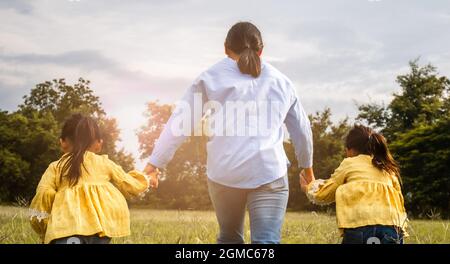 Mère et fille se tenant les mains et courant sur le terrain dans le parc d'été. Une famille heureuse passe son temps libre ensemble en vacances. Banque D'Images