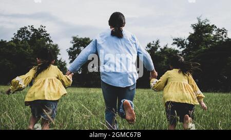 Mère et fille se tenant les mains et courant sur le terrain dans le parc d'été. Une famille heureuse passe son temps libre ensemble en vacances. Banque D'Images