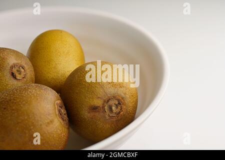 Bol de baies entières de kiwis doré (Actinidia chinensis) sur fond blanc Banque D'Images