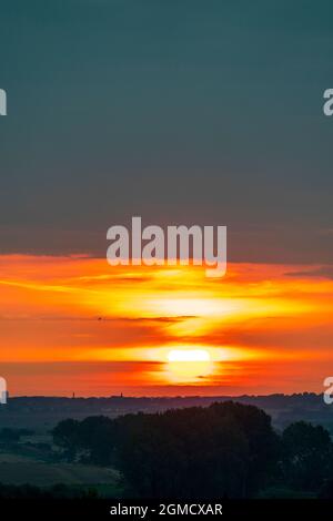 Lever du soleil sur la ville de Margate, dans le Kent, vue depuis le village de Reculver.Soleil se levant dans une bande étroite de ciel rouge vif avec quelques nuages et au-dessus des nuages épais de pluie sombre remplissant le ciel. Banque D'Images