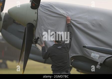 IWM Duxford, Cambridgeshire, Royaume-Uni. 18 septembre 2021. Un début malin alors que le spectacle aérien de la bataille de Grande-Bretagne aura lieu du 18-19 au 22 septembre à IWM Duxford, L'ancien site de la RAF qui a joué un rôle central dans certains des jours les plus dramatiques de l'histoire du XXe siècle - servant de base à de nombreux pilotes de Spitfire et d'ouragan pendant la Seconde Guerre mondiale. La bâche étant retirée du fuselage d'un Spitfire Supermarine avant l'exposition de vol. Crédit : Malcolm Park/Alay Live News Banque D'Images