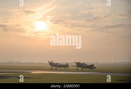 IWM Duxford, Cambridgeshire, Royaume-Uni. 18 septembre 2021. Un début malin alors que le spectacle aérien de la bataille de Grande-Bretagne aura lieu du 18-19 au 22 septembre à IWM Duxford, L'ancien site de la RAF qui a joué un rôle central dans certains des jours les plus dramatiques de l'histoire du XXe siècle - servant de base à de nombreux pilotes de Spitfire et d'ouragan pendant la Seconde Guerre mondiale. Image: The Fighter Collection Curtiss P-40F Warhawk et Curtis Hawk 75 s'assoient sur l'aérodrome brumeux au lever du soleil. Crédit : Malcolm Park/Alay Live News Banque D'Images