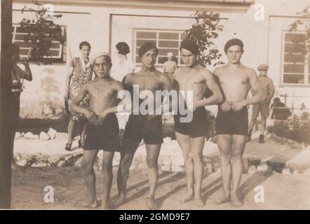 Rarement vu photo de 1933.les amis ou copains d'école posent dans un centre de vacances. Ils portent des bérets, et ils montrent à quel point ils sont forts. Les jeunes bodybuilders.onlookers sont à l'arrière-plan. Banque D'Images