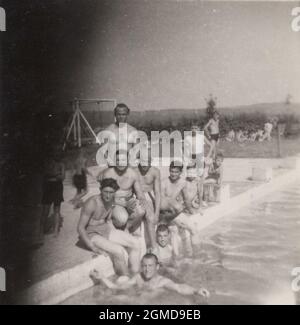 photo rétro monochrome originale d'un photographe professionnel, dont le doigt couvre presque la moitié de l'image. Des amis et des membres de la famille à la plage, à la piscine, et en essayant de poser pour le photographe. La prochaine fois, nous allons nous améliorer. (années 1950) Banque D'Images