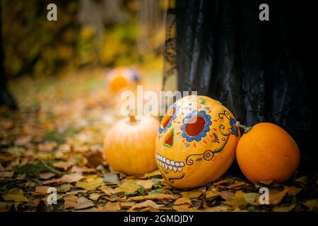 Trois citrouilles décorées pour Halloween se trouvent sur le feuillage jaune. Historique de la vente d'Halloween. Banque D'Images