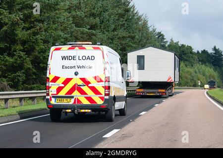 Véhicule d'escorte à grande charge voyageant derrière une caravane statique mobile home transporté à l'arrière du camion sur la route A9, Écosse, Royaume-Uni Banque D'Images