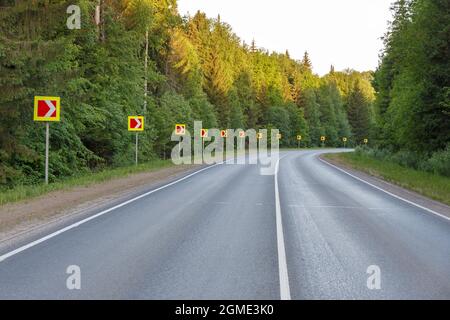 Signalisation routière signalant une courbe de route dangereuse. Virage dangereux dans la forêt. Banque D'Images