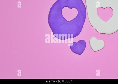 Vue de dessus et espace de copie pour le texte. Moule en argile violet et blanc en forme de coeur sur fond rose. Banque D'Images