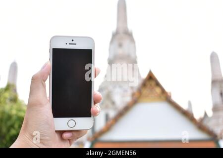 Une maquette de smartphone à main pour trouver le signal GPS et le temple thaïlandais en arrière-plan Banque D'Images