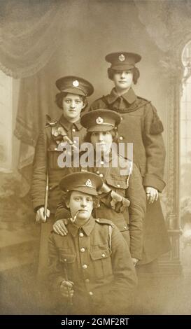 Un portrait de quatre dames dans les uniformes des soldats britanniques de la première Guerre mondiale. Les deux du milieu portent l'insigne de chapeau des Royal Engineers, la dame à la police a un insigne de chapeau victorien du East Lancashire Regiment. La dame à l'arrière semble avoir accessorisé son uniforme avec ce qui semble être un tassle de rideau. Banque D'Images