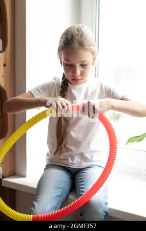 jouet en plastique anti-stress tube pop sensoriel dans les mains des enfants. une petite fille heureuse joue avec un jouet de violon de tube à pression à la maison. les enfants tiennent et jouent Banque D'Images