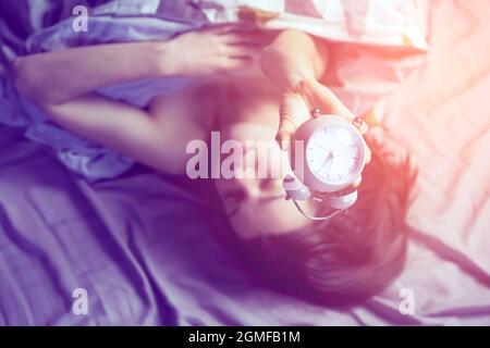 Une jeune fille tient un réveil vintage dans ses mains. Banque D'Images