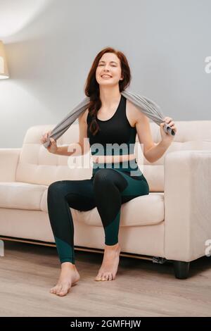 L'athlète est assis sur le canapé avec une serviette après des exercices de fitness intensifs. Banque D'Images