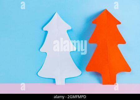 Arbres de Noël en papier sur fond bleu-rose. Arbres de noël en papier blanc et rouge. Noël concept minimal Banque D'Images