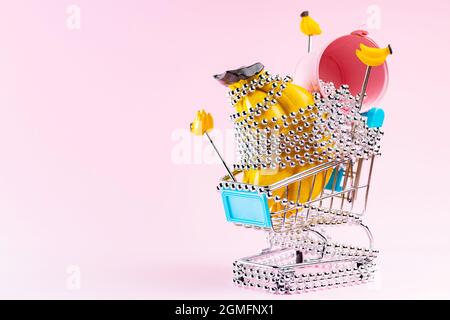 Chariot de magasinage avec perles argentées de Noël sur fond rose. Panier avec cadeaux de Noël créatifs. Concept de décoration de Noël Banque D'Images