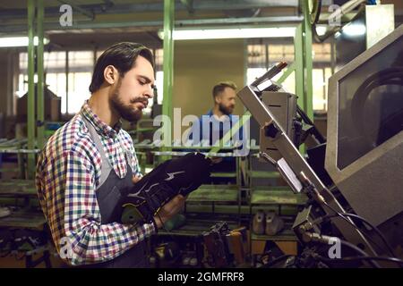 Travailleur qui fabrique de nouvelles baskets et qui utilise des machines industrielles spéciales à l'usine de chaussures Banque D'Images
