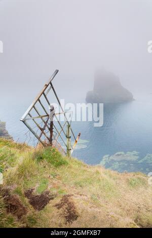 Vieille porte tombant du bord de la falaise à Duncansby Head et piles de mer, à proximité de John O Groats, Caithness, nord-est de l'Écosse avec un fret de mer. Banque D'Images