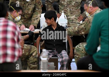 Ramstein-Miesenbach, Allemagne. 18 septembre 2021. Un aviateur de la US Air Force administre des vaccins contre les oreillons, la rougeole et la rubéole et contre la varicelle à un enfant afghan évacué de Kaboul à la base aérienne de Ramstein le 17 septembre 2021 à Ramstein-Miesenbach, en Allemagne. Ramstein fournit un hébergement temporaire aux personnes évacuées d'Afghanistan dans le cadre de l'opération alliés refuge. Crédit : TSgt. Devin Nothstine/États-Unis Air Force/Alamy Live News Banque D'Images