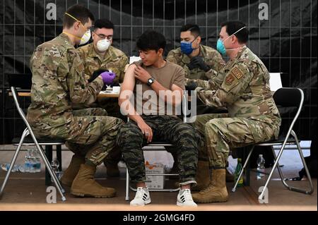 Ramstein-Miesenbach, Allemagne. 18 septembre 2021. Un aviateur de la US Air Force administre des vaccins contre les oreillons, la rougeole et la rubéole et contre la varicelle à un enfant afghan évacué de Kaboul à la base aérienne de Ramstein le 18 septembre 2021 à Ramstein-Miesenbach, en Allemagne. Ramstein fournit un hébergement temporaire aux personnes évacuées d'Afghanistan dans le cadre de l'opération alliés refuge. Crédit : TSgt. Devin Nothstine/États-Unis Air Force/Alamy Live News Banque D'Images