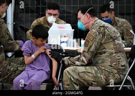 Ramstein-Miesenbach, Allemagne. 18 septembre 2021. Un aviateur de la US Air Force administre des vaccins contre les oreillons, la rougeole et la rubéole et contre la varicelle à un enfant afghan évacué de Kaboul à la base aérienne de Ramstein le 18 septembre 2021 à Ramstein-Miesenbach, en Allemagne. Ramstein fournit un hébergement temporaire aux personnes évacuées d'Afghanistan dans le cadre de l'opération alliés refuge. Crédit : TSgt. Devin Nothstine/États-Unis Air Force/Alamy Live News Banque D'Images