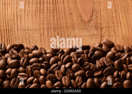 Saupoudrer les grains de café au bas de la photo. La moitié supérieure de la photo est un arrière-plan en bois marron vide Banque D'Images