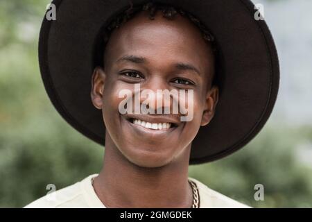 Jeune homme hippster africain souriant sur la caméra en plein air au parc de la ville - Focus sur le visage Banque D'Images