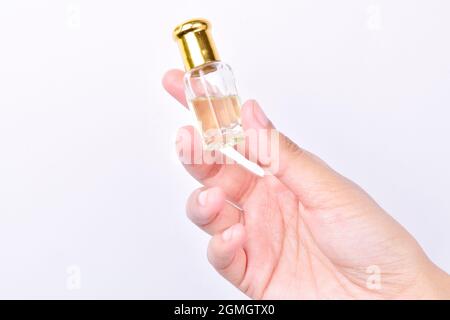 bouteille d'huile essentielle à la main isolée sur fond blanc, huile aromatique ou bouteille de parfum attar dans la main de la femme sur fond blanc Banque D'Images