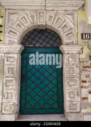 Ancienne porte en métal vert avec treillis dans une ancienne arche ronde Banque D'Images